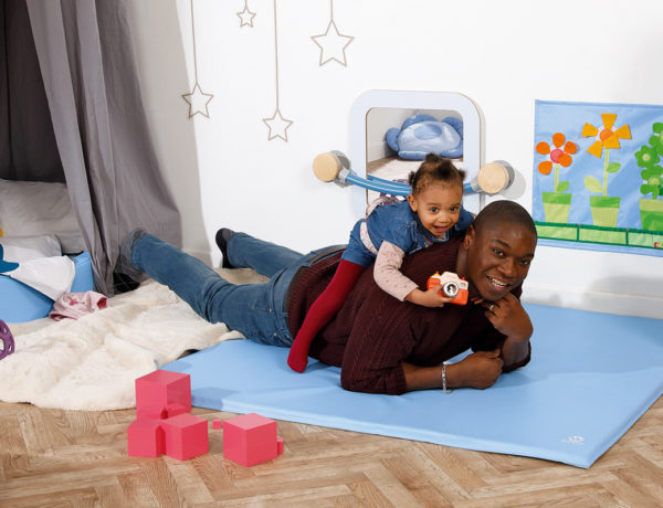 homme avec enfant sur le dos dans une chambre d'enfant sur tapis aménager une chambre Montessori blog wesco