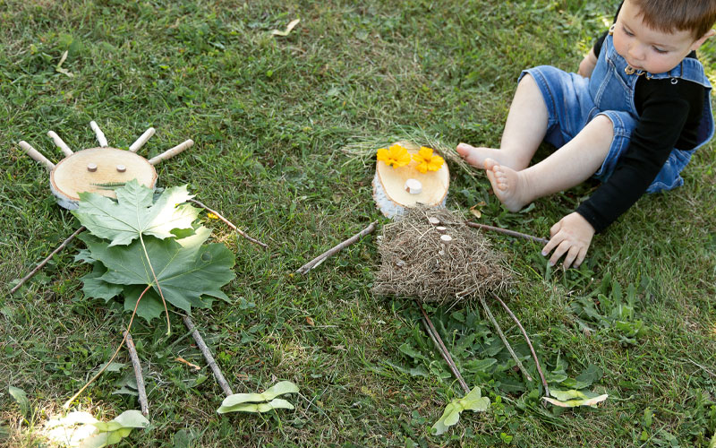 Enfant 2 ans qui réalise une activité de land art sur l'herbe blog Wesco