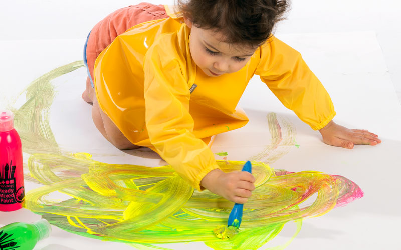 Fille qui fait de la peinture avec une blouse jaune blog wesco